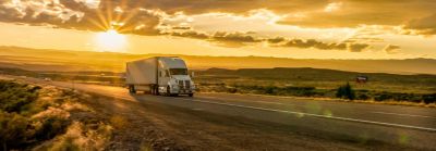 semi-truck on highway with landscape at sunrise