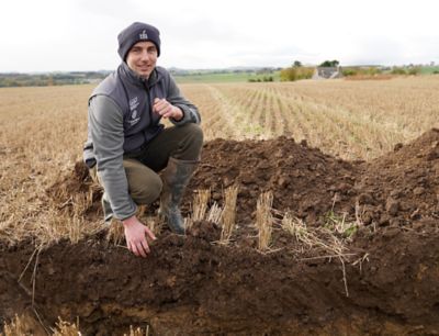 Ben Lowe looking at top soil in a soil pit