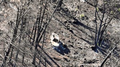 A burned-out vehicle sits among the Park Fire debris.