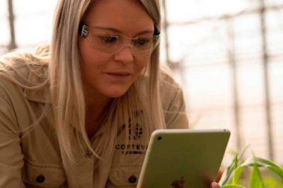 Woman examining indoor plants with iPad
