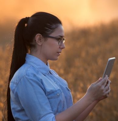 woman viewing iPhone in field at sunrise