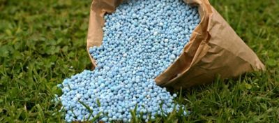 fertilizer spilling from a brown bag onto the grass