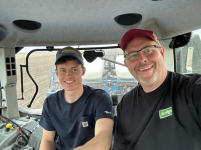 Jacob Belzer and his father Bill Belzer inside the cabin of a tractor