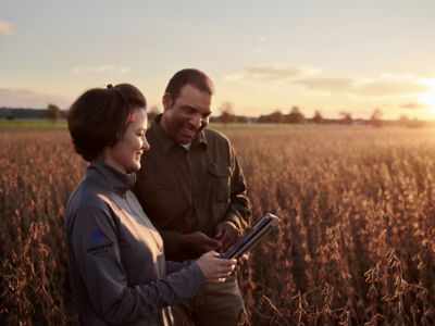 Man and woman inspecting field at sunrise
