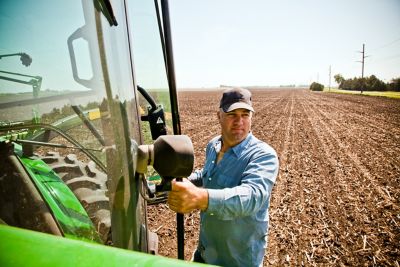 Farmer climbing into tractor cab