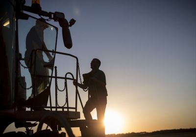 Farmers in tractor cab at sunrise