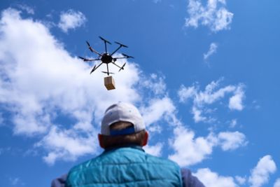 Drone up in the sky carrying a package for delivery
