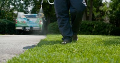 Lawn care operator spraying lawn near driveway