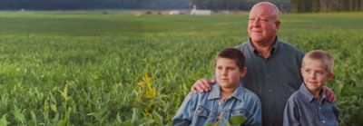 Father and two sons seated in crop field
