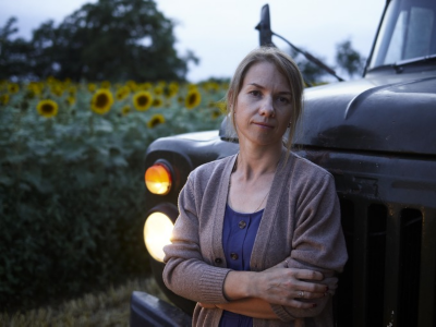 Woman standing infront of a truck parking infront of a field of sunflowers