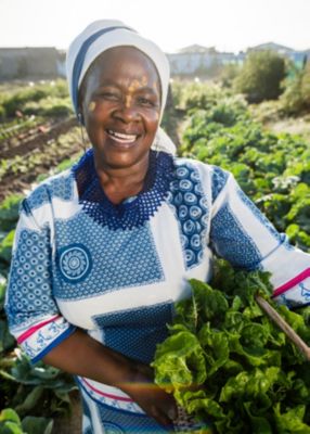 Smiling female farmer holding crops