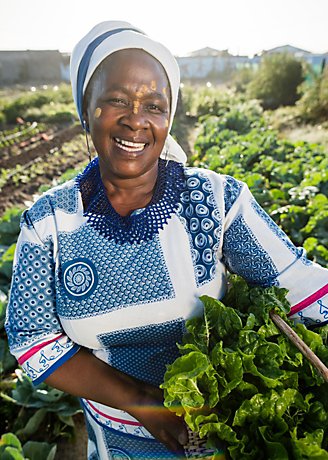 Smiling female farmer holding crops