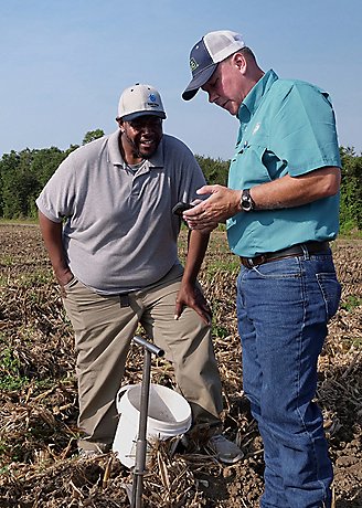two men in field viewing data on phone