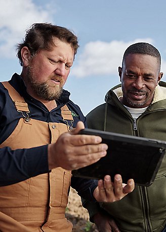 two men in field viewing data on tablet