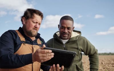 two men in field viewing data on tablet