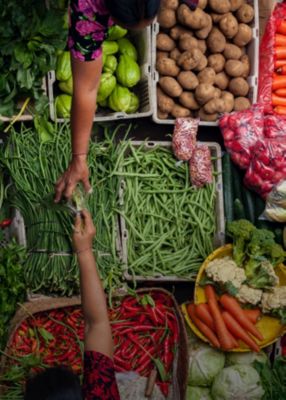 Arms reaching across market vegetables