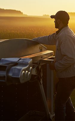 Farmer on back of grain truck at sunset