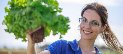 Woman smiling holding up a lettuce