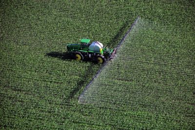 Aerial view of green tractor sprayer in field