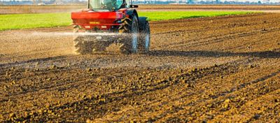 Trator espalhando fertilizantes na lavoura