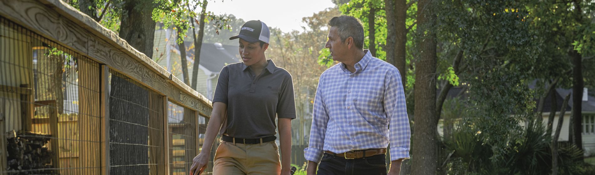 Certified Sentricon Specialist walking fenceline with homeowner