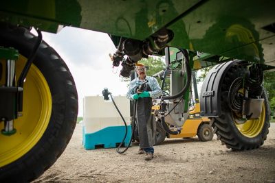 Farmer filling sprayer from Enlist tote