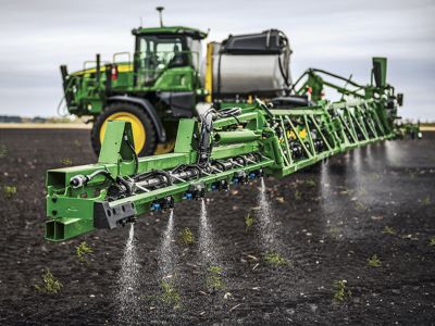 Green tractor sprayer applying herbicides
