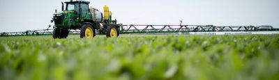 Green tractor sprayer in Enlist field