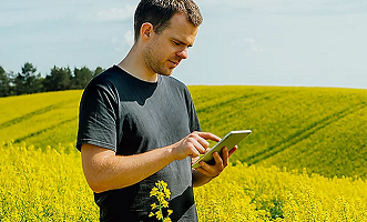 man in crop field working on tablet