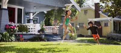 Picture of a home with a boy and girl running through a sprinkler