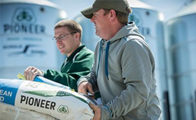 Farmers unloading bags of Pioneer brand Enlist E3 soybean seeds.