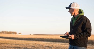 Photo - man with tablet - standing by harvested cornfield