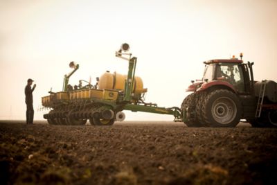 Farmer behind planter in field at sunrise