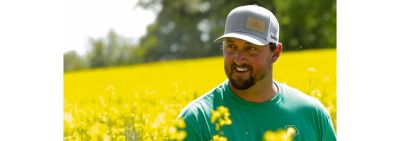 A farmer inspecting a canola crop in a field.