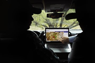 2 ranchers in a truch looking at an ipad