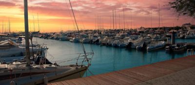 Sailboats docked at marina at sunset