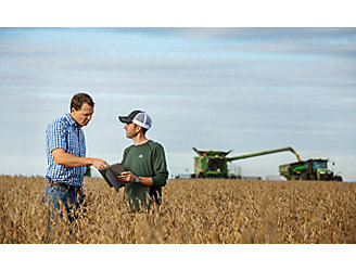 Representative and farmer talking in soybean field