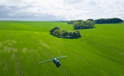 Tractor spraying wheat field