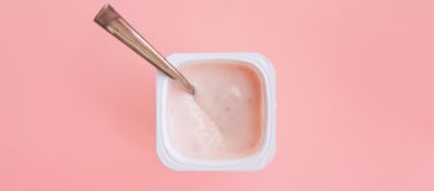 strawberry yogurt in plastic cup with spoon, view from above