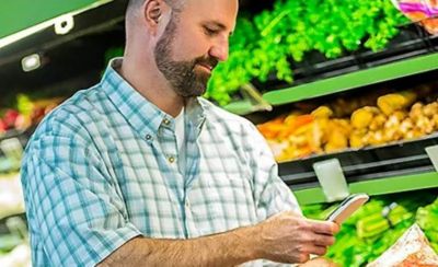 Man looking at phone in produce section of grocery store