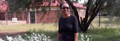 woman farmer in field with house in background