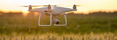 Drown flying over field at sunrise