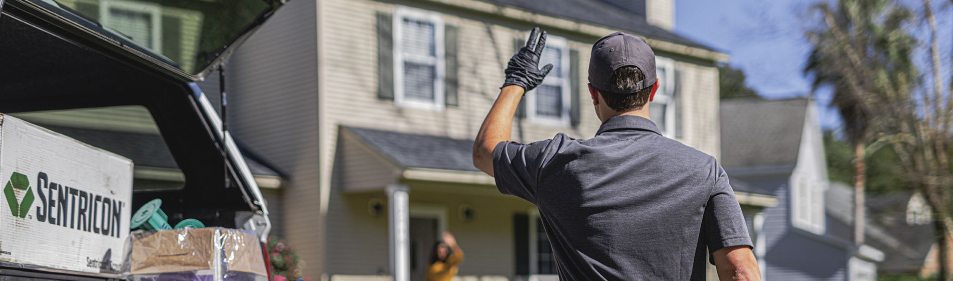 Sentricon certified specialists waves to homeowners from back of his truck