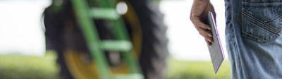 Farmer with tablet and green tractor in background