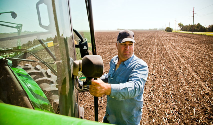 Farmer climbing into tractor cab