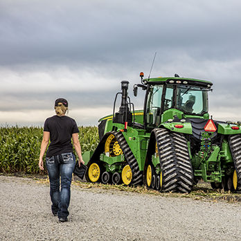 Farmer walking next to green tractor