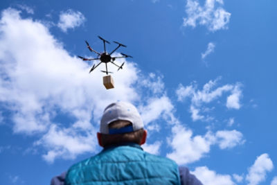 Drone up in the sky carrying a package for delivery
