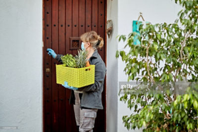 Home_food_delivery - woman ringing doorbell to deliver crate of food