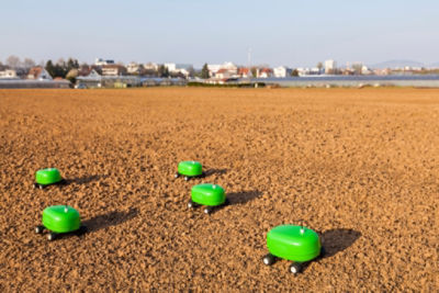 small automated bright green vehicles in dirt field