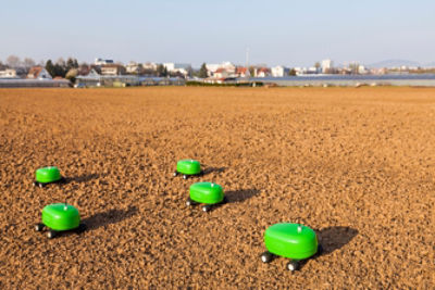 small automated bright green vehicles in dirt field